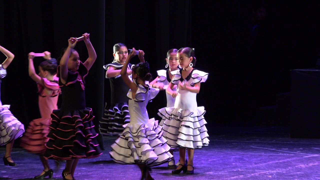 Children raise their arms while dancing in costume.