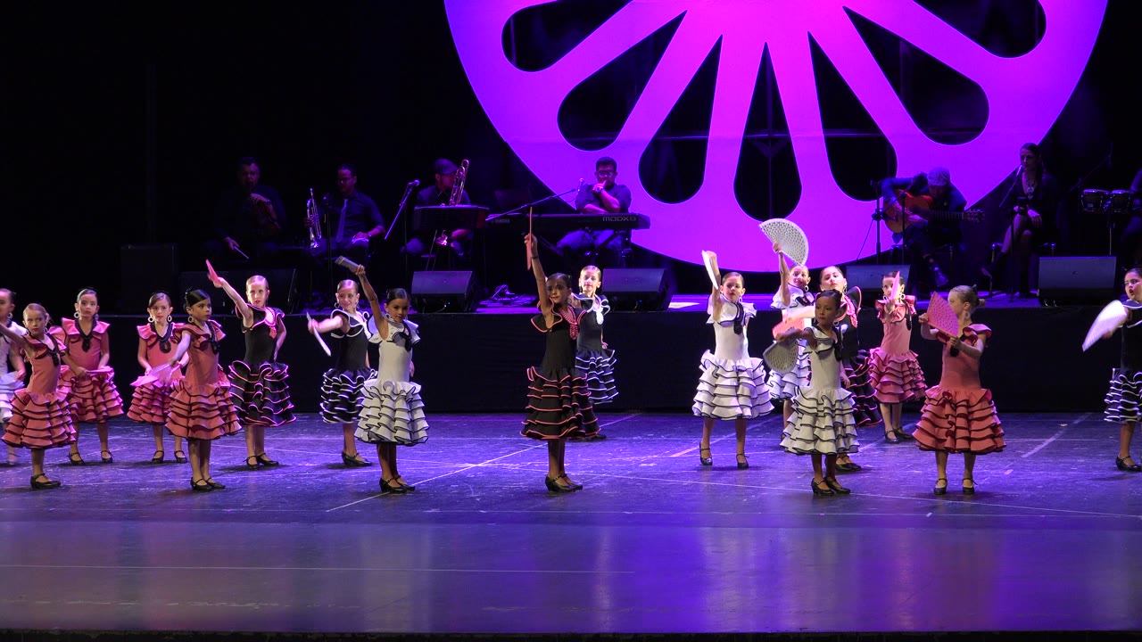 Performers raise fans during a stage dance routine.