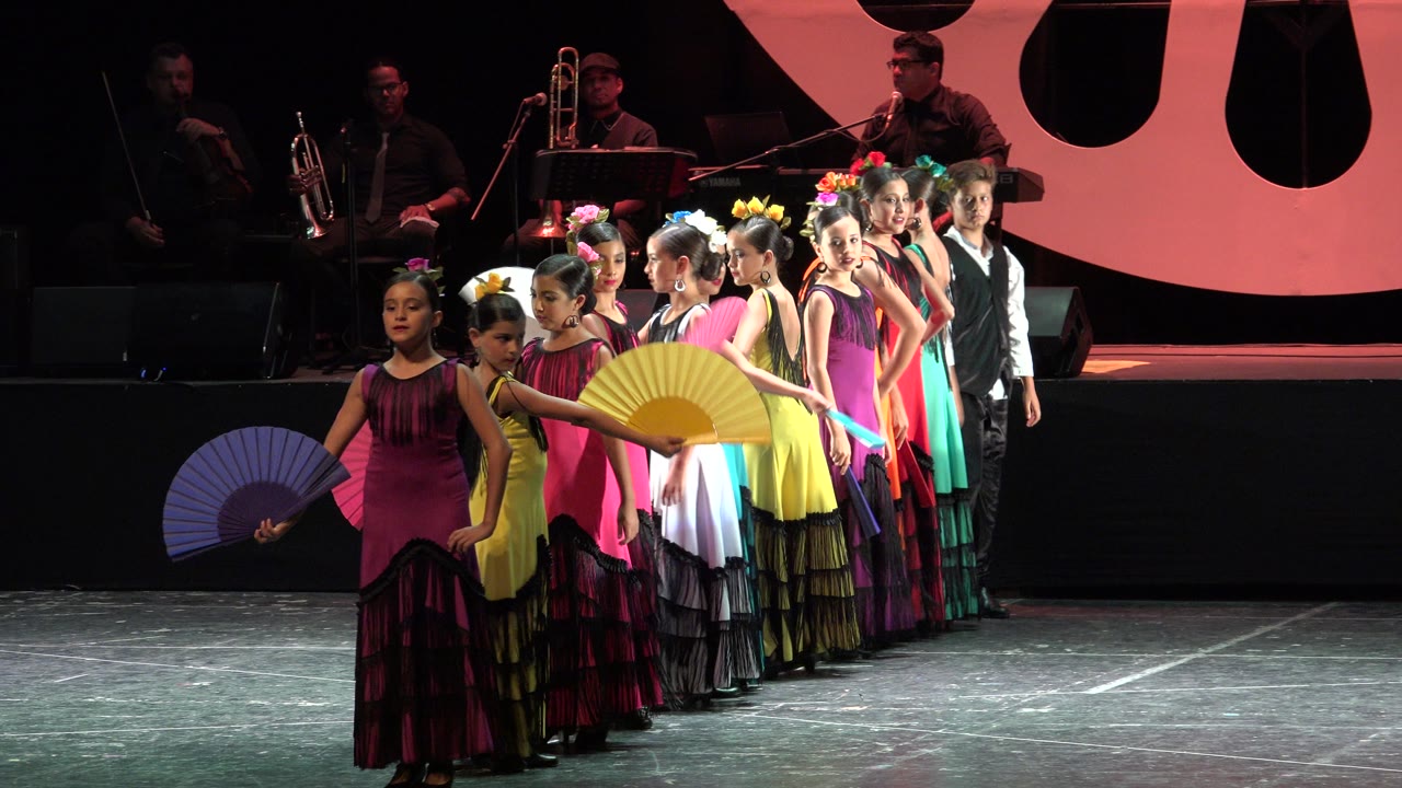 Girls begin raising colorful folding fans during the stage dance.