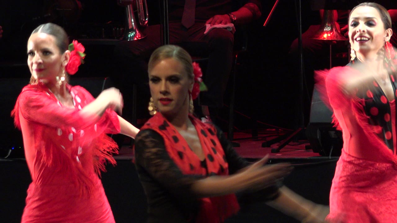 Three women perform with one dancer turning in profile and another facing the camera.