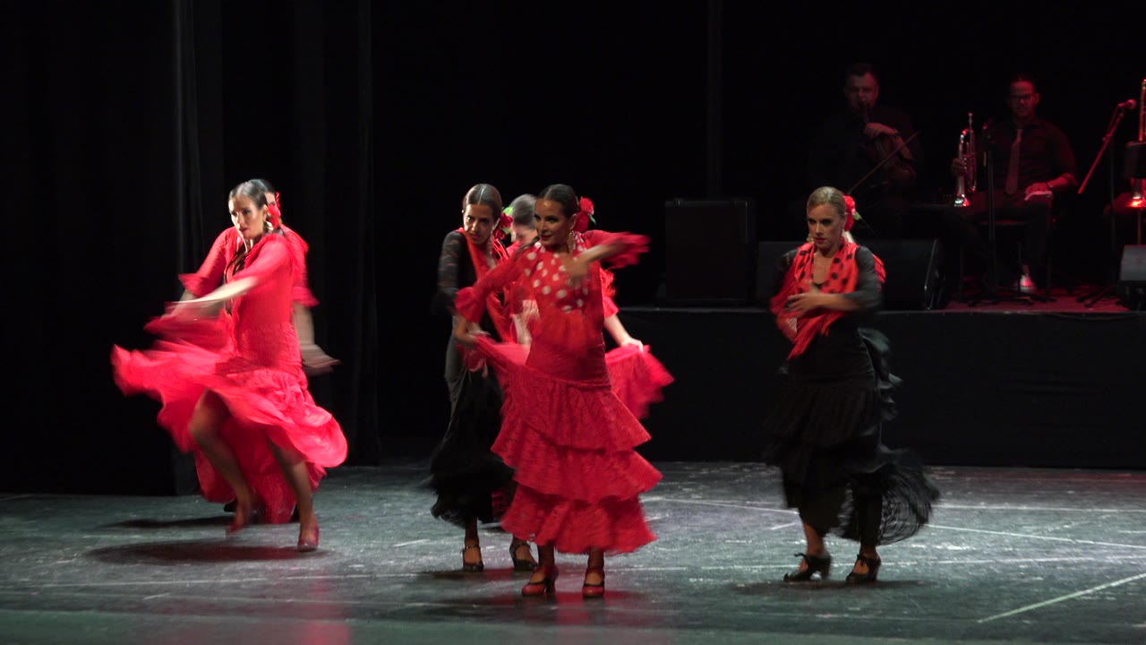 One dancer in red turns while others gather to the side.