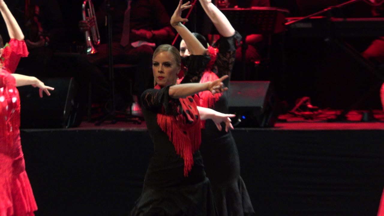 Women in black and red flamenco costumes performing on a dark stage