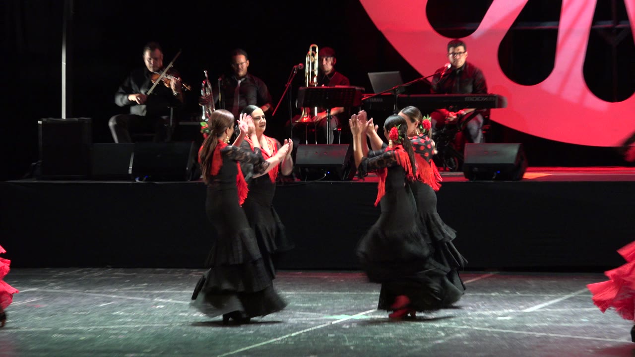 In Cabo San Lucas, Mexico, four dancers gather near center stage as the violinist, trumpet player, percussionist, and keyboard player remain visible behind them.