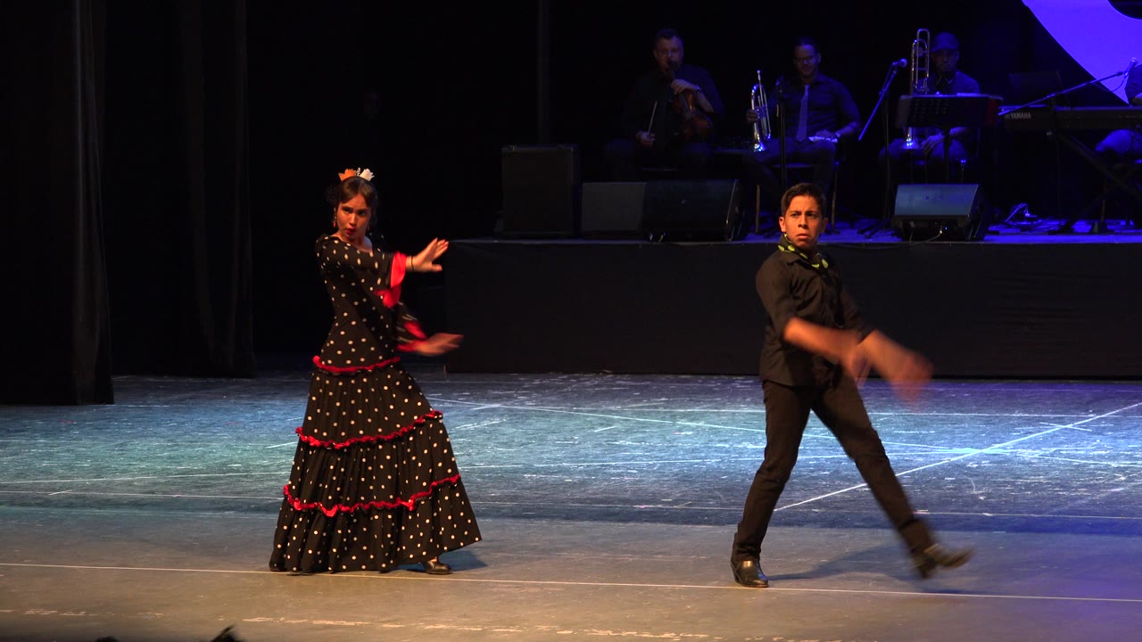 In Cabo San Lucas, Mexico, the woman keeps one arm extended as the man steps across the stage, with the band still visible on the raised platform behind them.