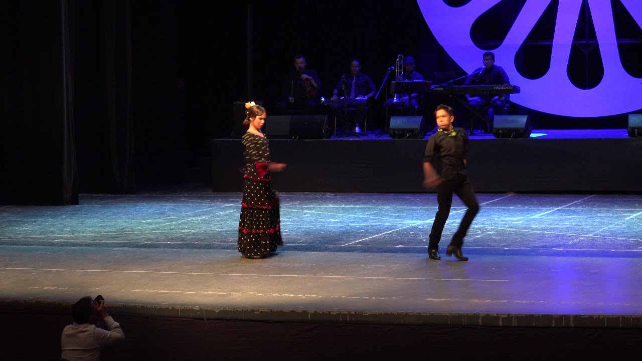 Boy and girl facing each other on a lit theater stage.