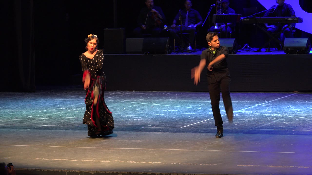 Female dancer and male partner shift positions during a stage performance.