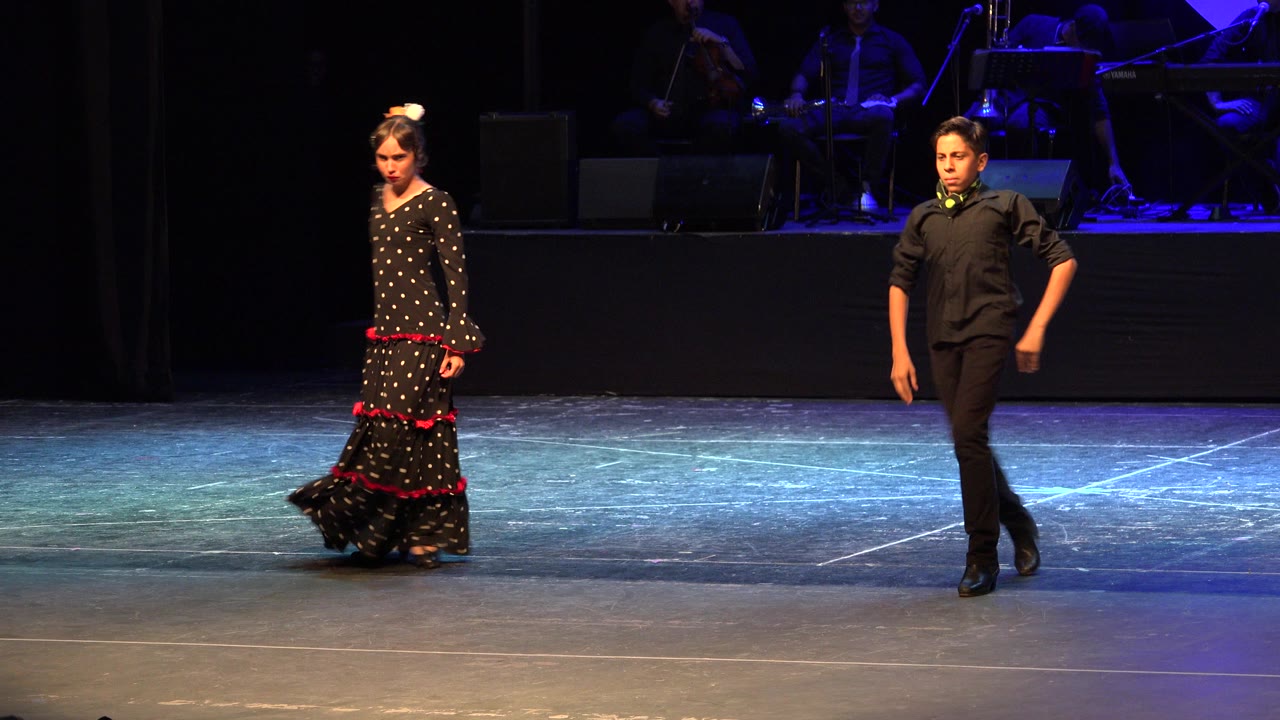 The two performers remain separated across the stage in Cabo San Lucas, Mexico, with the girl stepping in her ruffled dress and the boy moving forward in black.