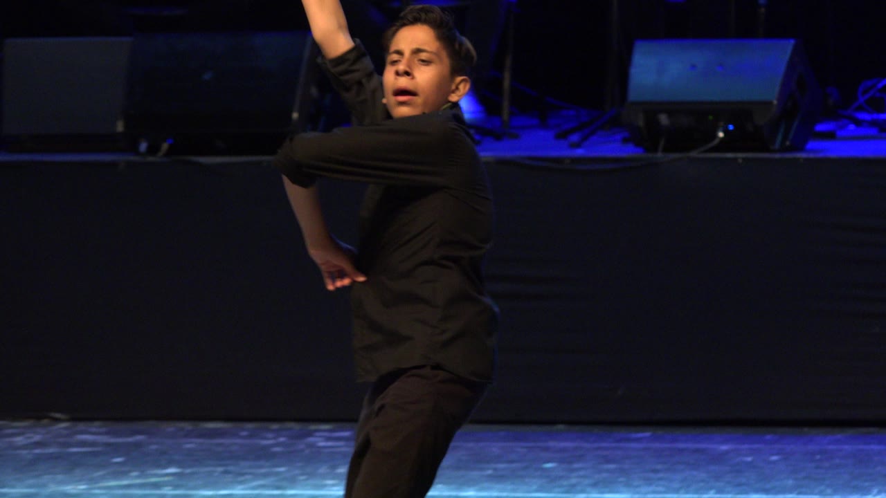 Boy turns during a stage dance pose.