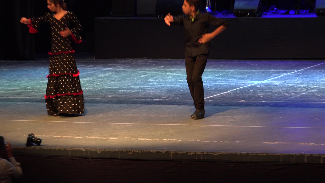 Boy and girl dancing on a lit stage.