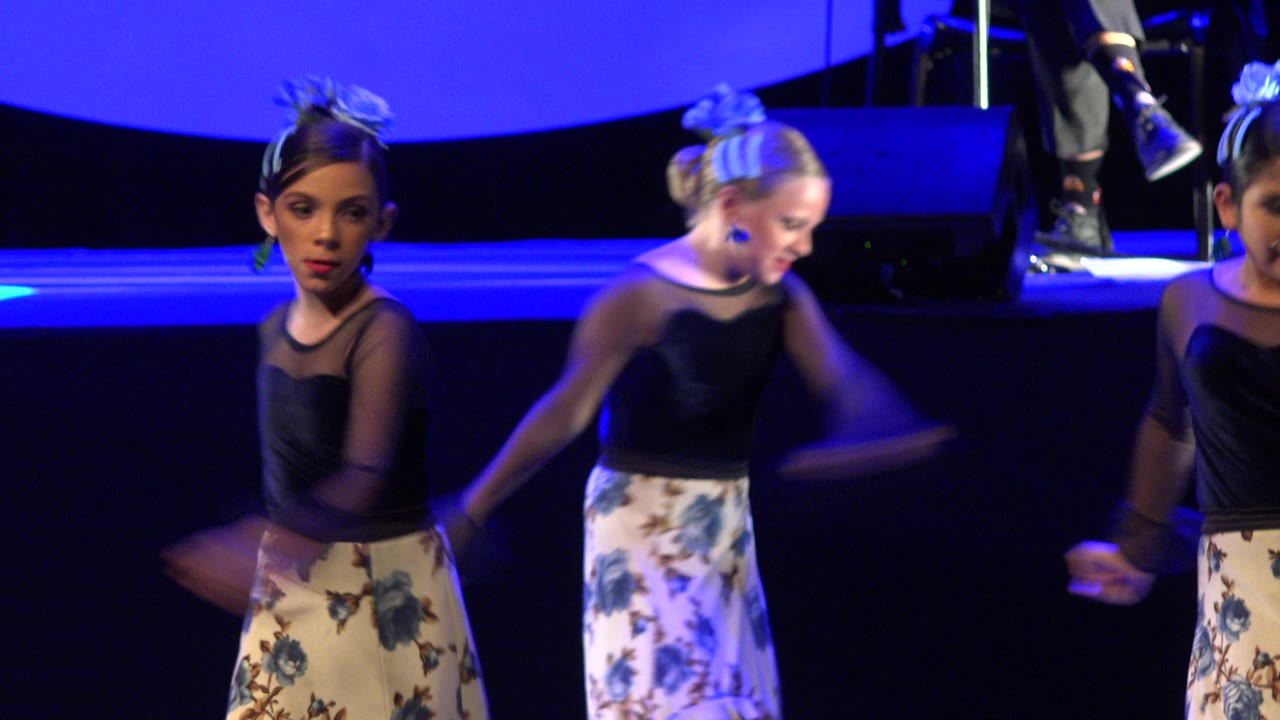 Two young girls dancing on a blue-lit stage