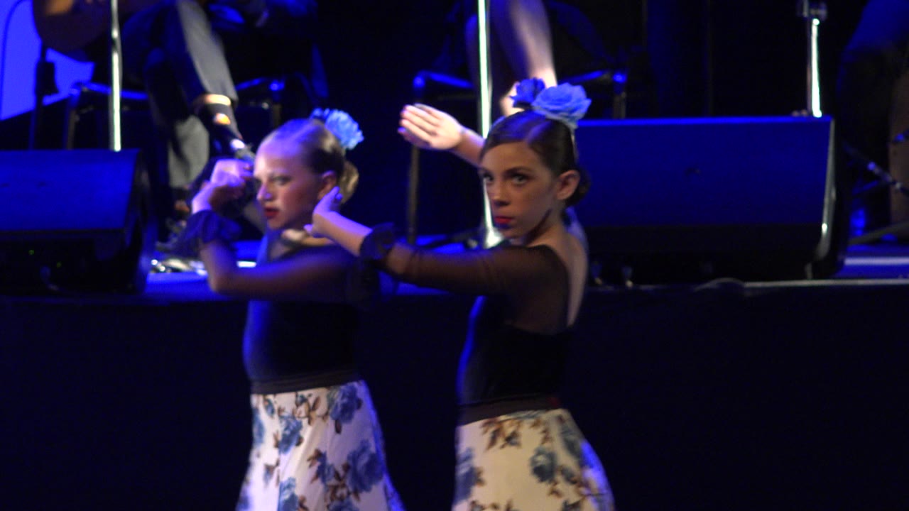Two young girls dancing on a blue-lit stage