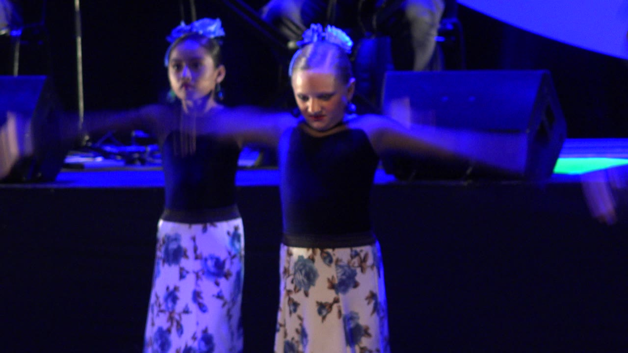 Two girls dancing on a blue-lit stage.