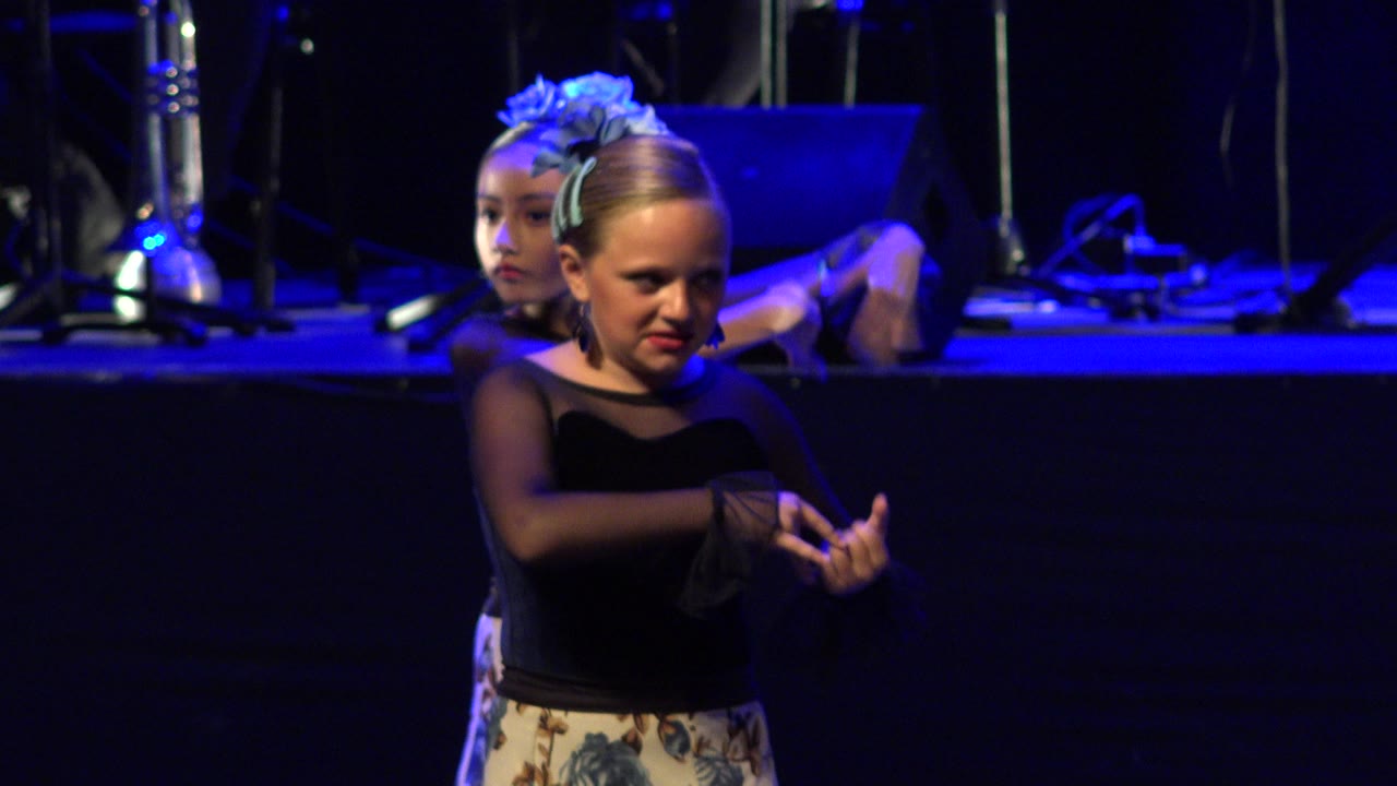 Two girls on stage with the front dancer holding her hands forward.
