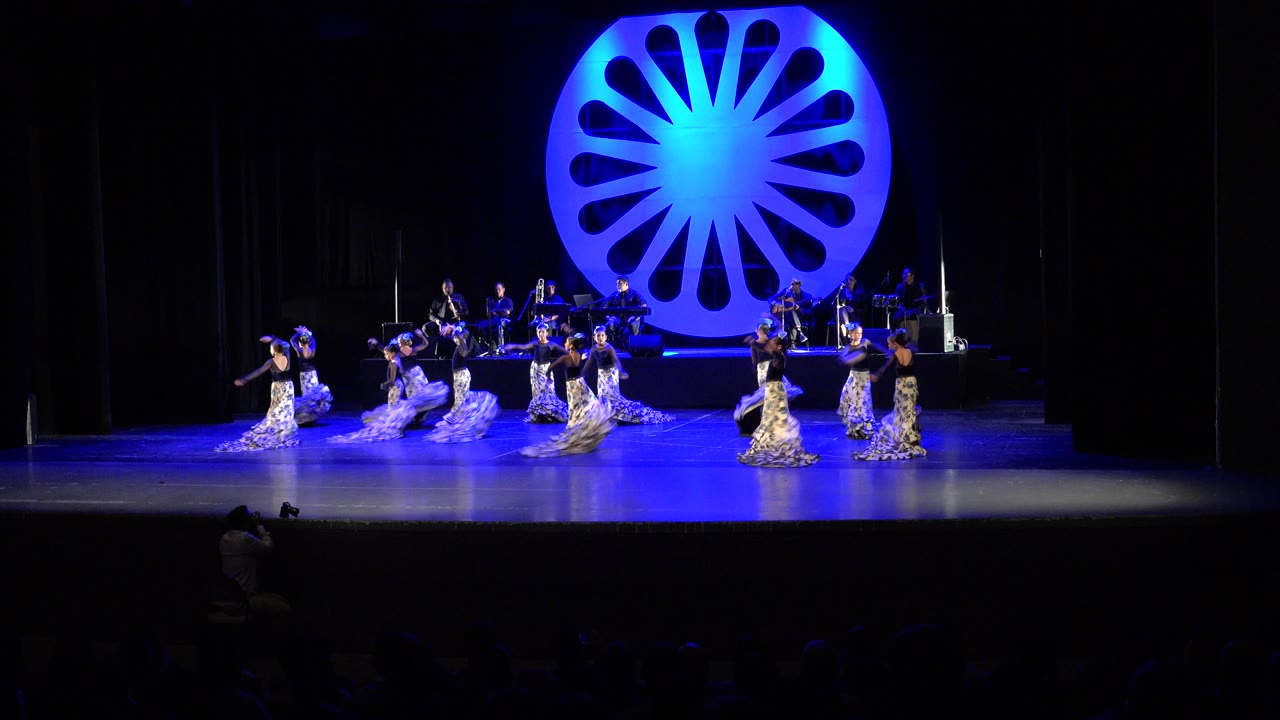 Wide stage with flamenco-style dancers under blue lighting