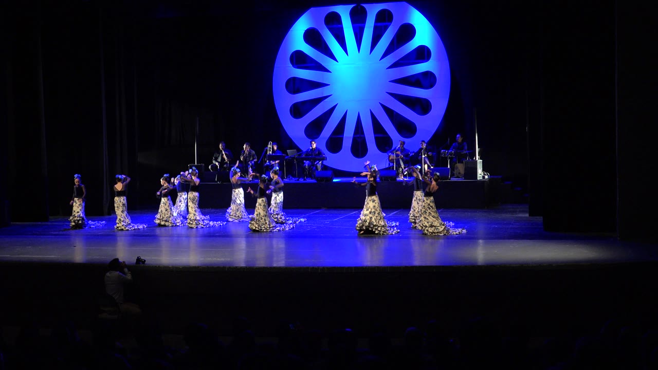 Wide theater stage with young dancers and a blue circular backdrop.