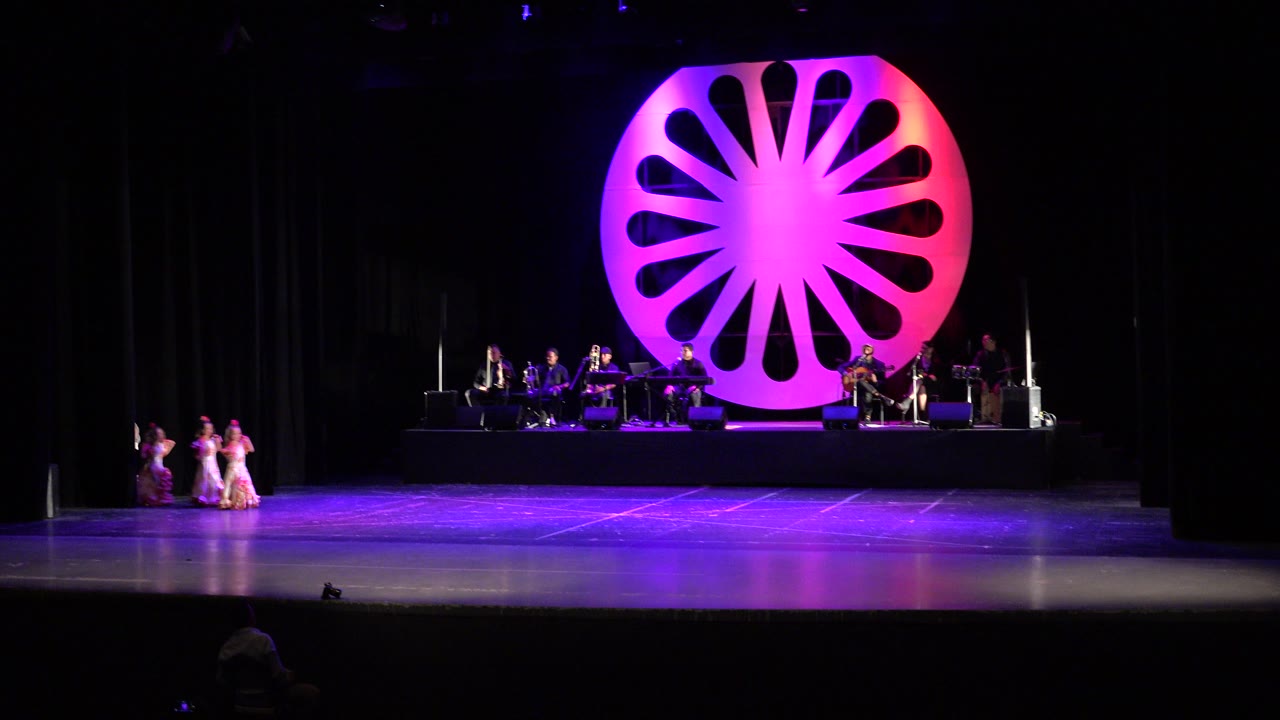 Women in pink and gold dresses entering a purple-lit stage.