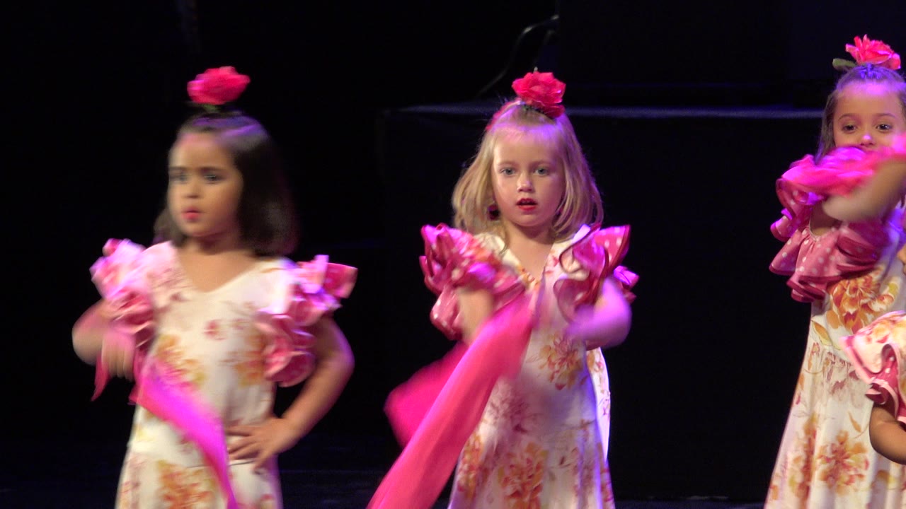 The Cabo San Lucas performance frame centers on two young girls in floral costumes while another child appears at the edge holding a pink scarf.