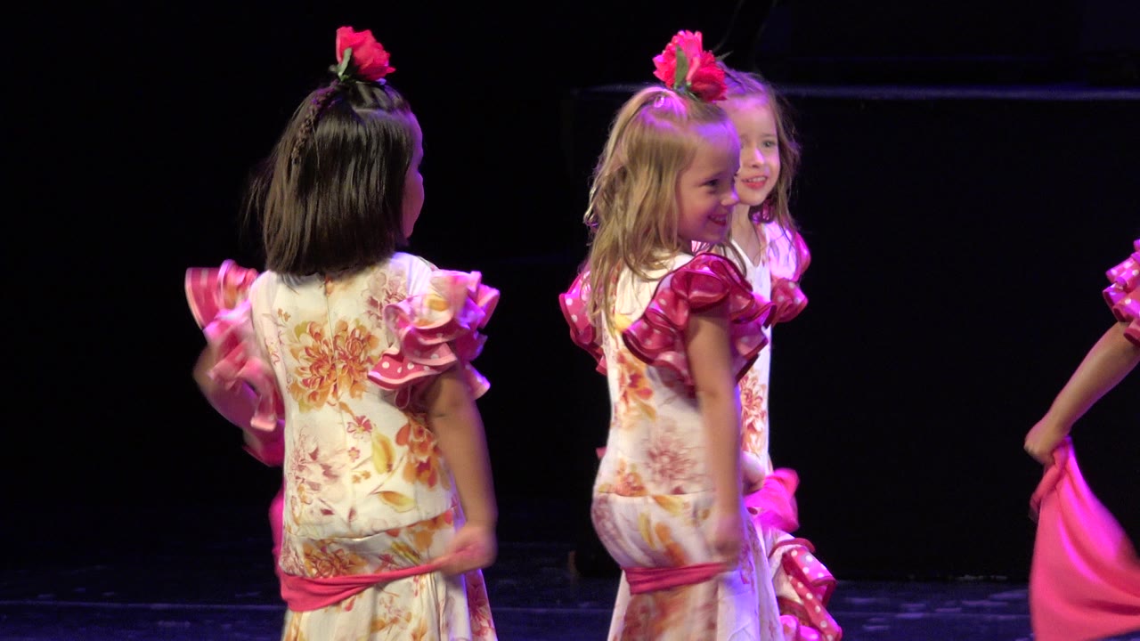 At 0:02 in Cabo San Lucas, Mexico, the girls turn toward the right side of the stage, with one child smiling and pink fabric entering from the edge.