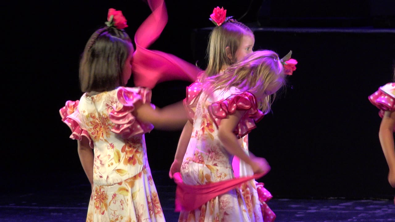 Girls bend and move pink fabric during a stage routine.