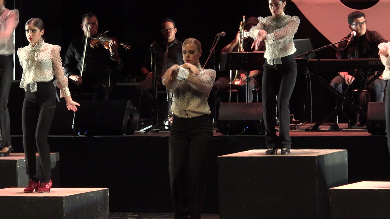 Dancers on stage with musicians behind them.
