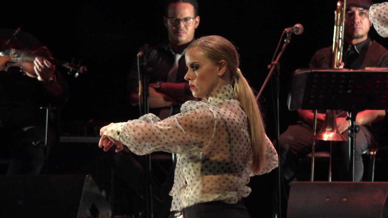 Dancer turns slightly with one arm extended across the stage.