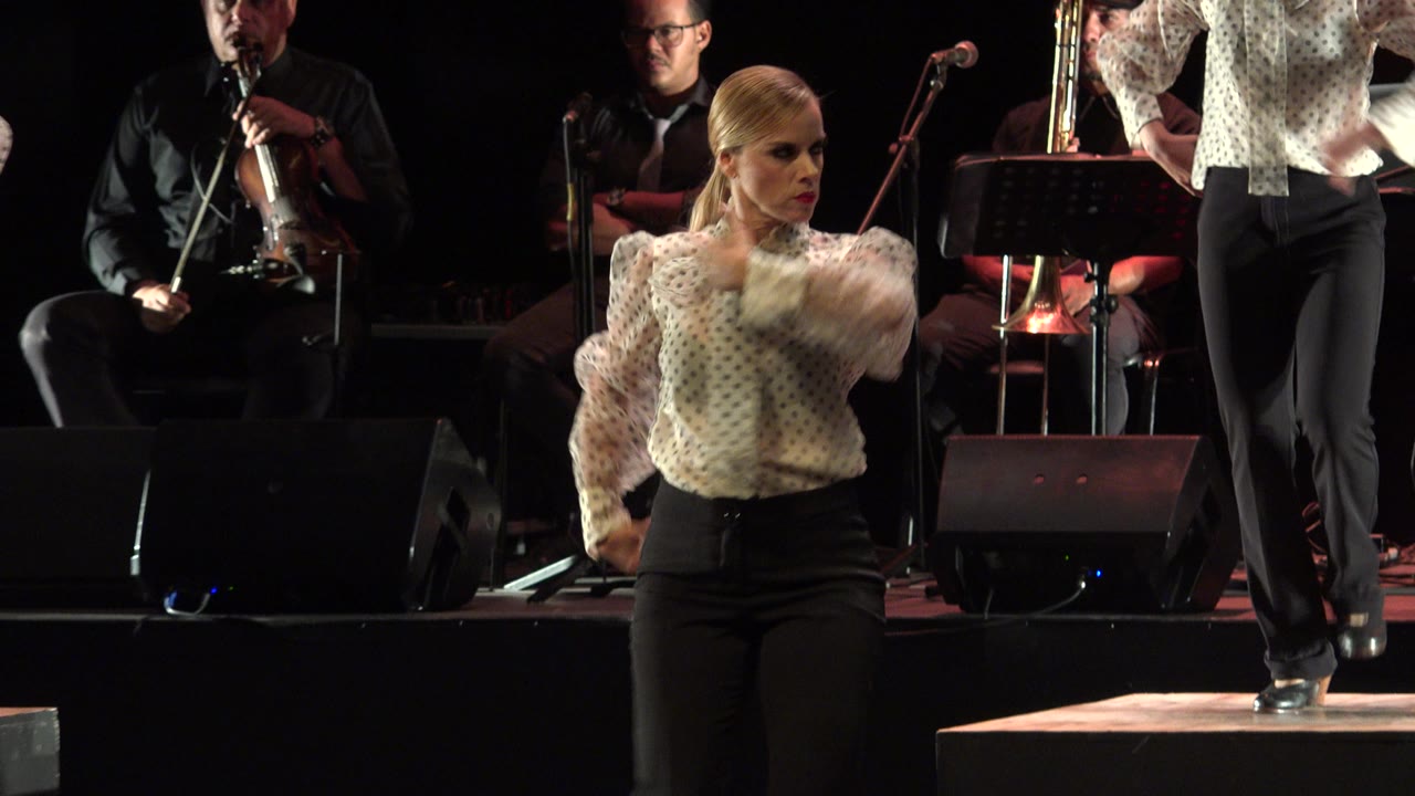 Woman turns during the dance with another performer partly visible.