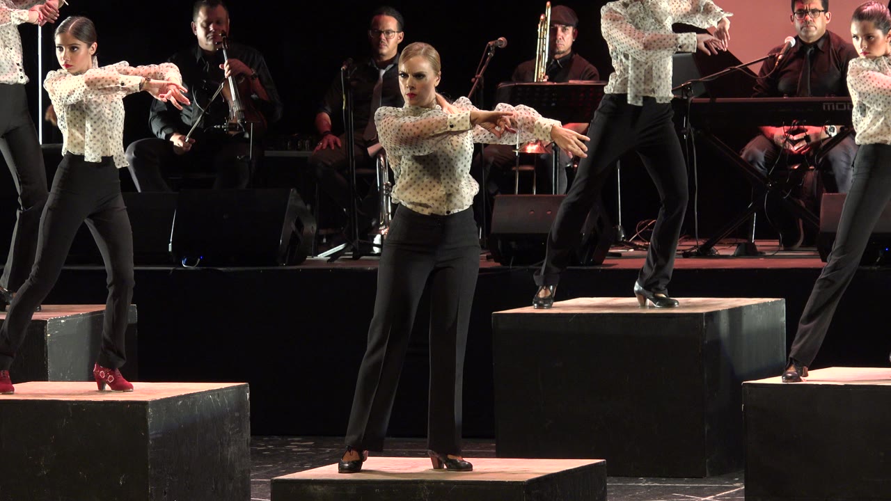 Flamenco dancers on stage with musicians behind them