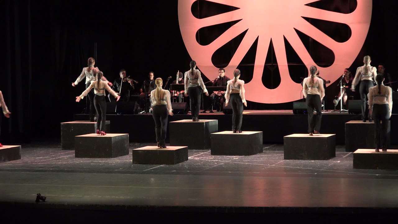 At 0:01 in Cabo San Lucas, Mexico, the dancers remain spread across raised black cubes while the band area and large pink circular set piece fill the rear of the stage.