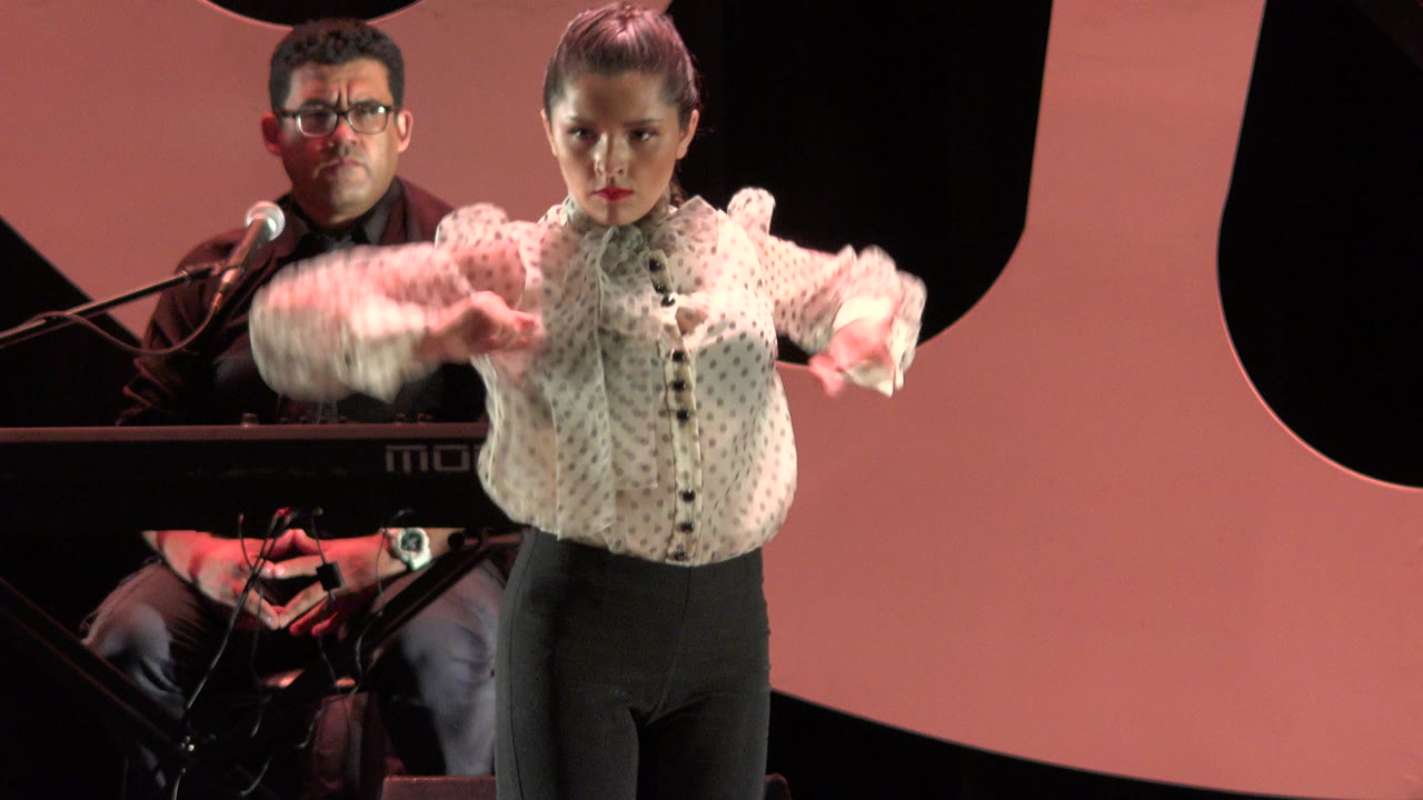 In Cabo San Lucas, Mexico, the dancer begins an arm movement with both sleeves lifted as the keyboard player is partly visible behind the stage keyboard.