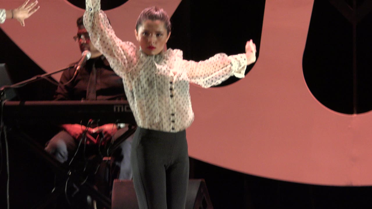 Female dancer with raised arms on a lit stage