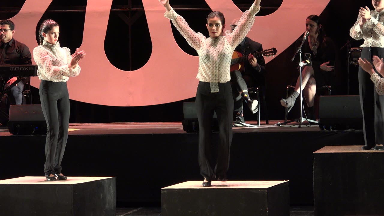 Woman claps while tap dancing near musicians onstage.