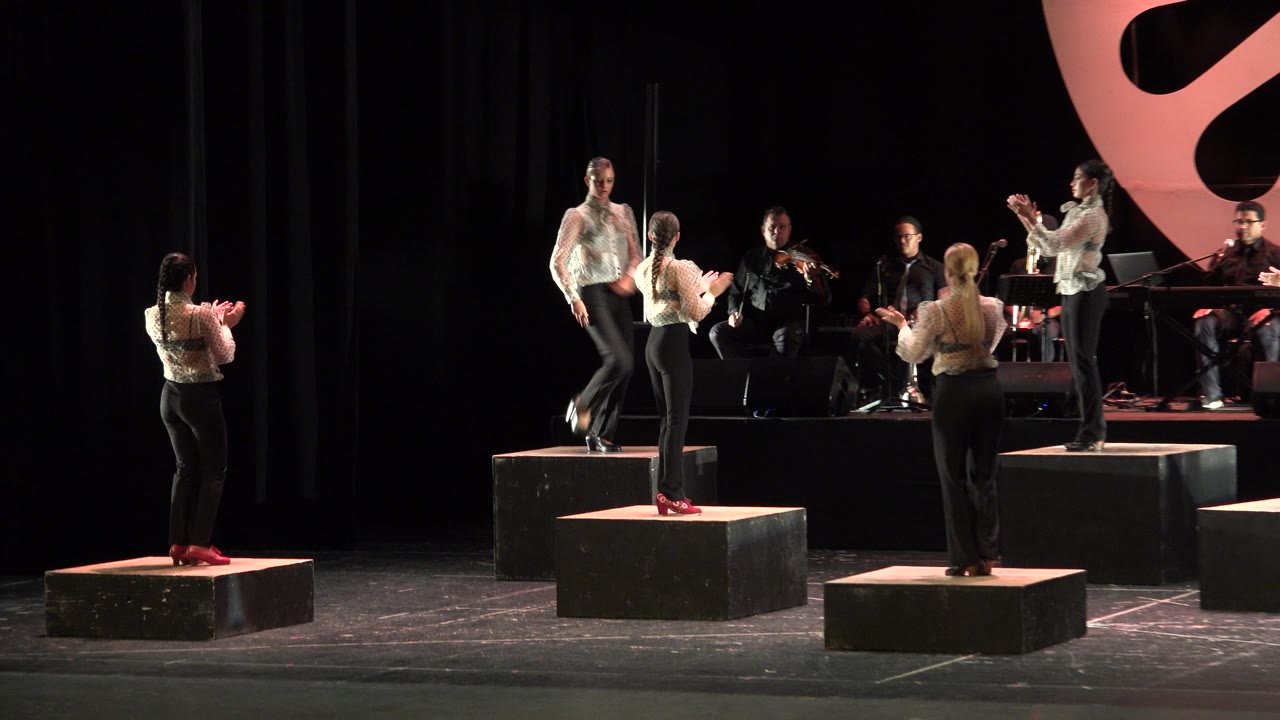 Flamenco dancers on raised platforms with musicians behind them.