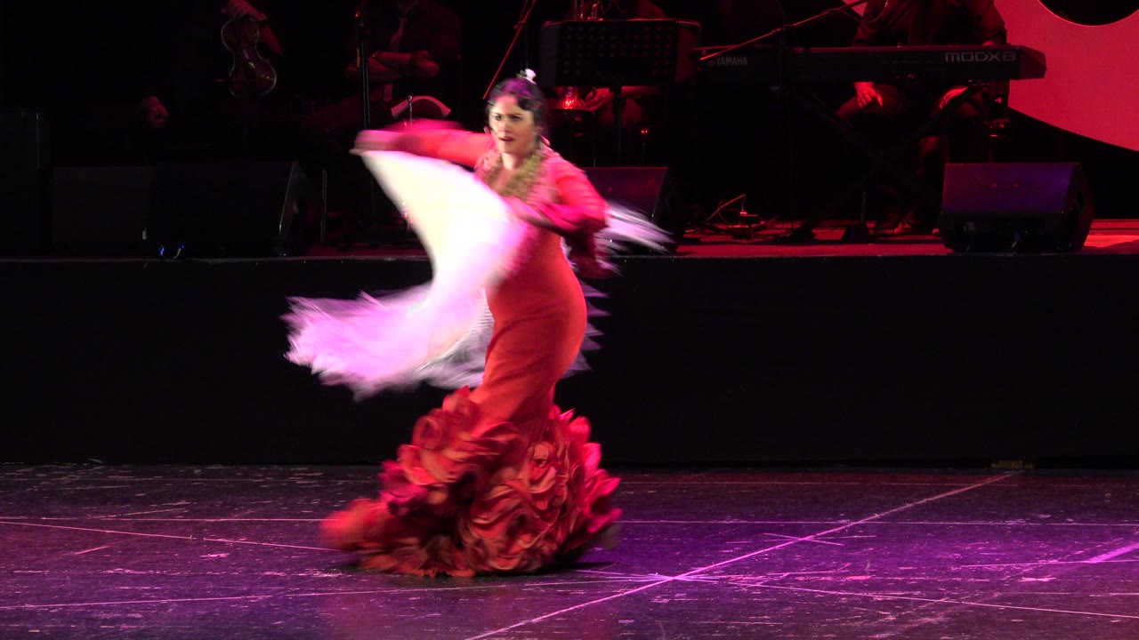 The Cabo San Lucas stage dancer moves left across the frame as her white shawl blurs in a sweeping arc against the dark band area.