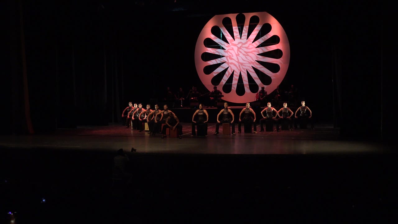 Wide stage view with performers beneath a pink circular set piece.
