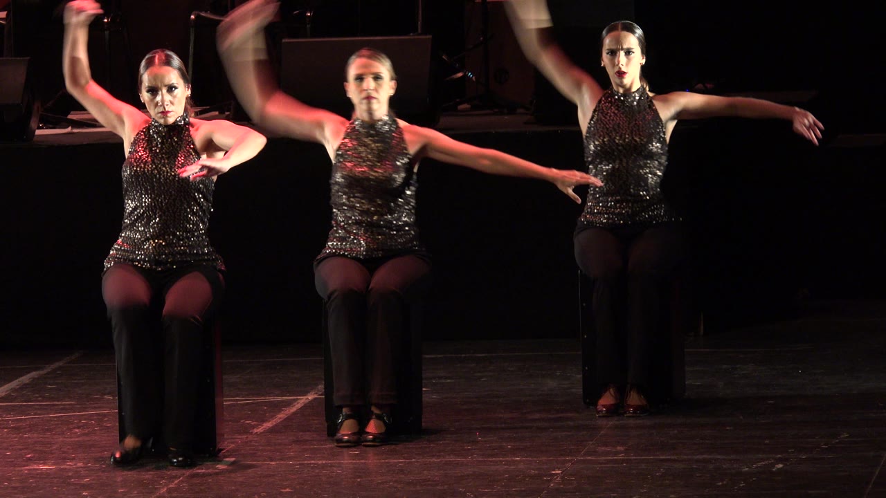 The Cabo San Lucas performance continues with three seated women facing forward while their arms move through a coordinated stage pose.
