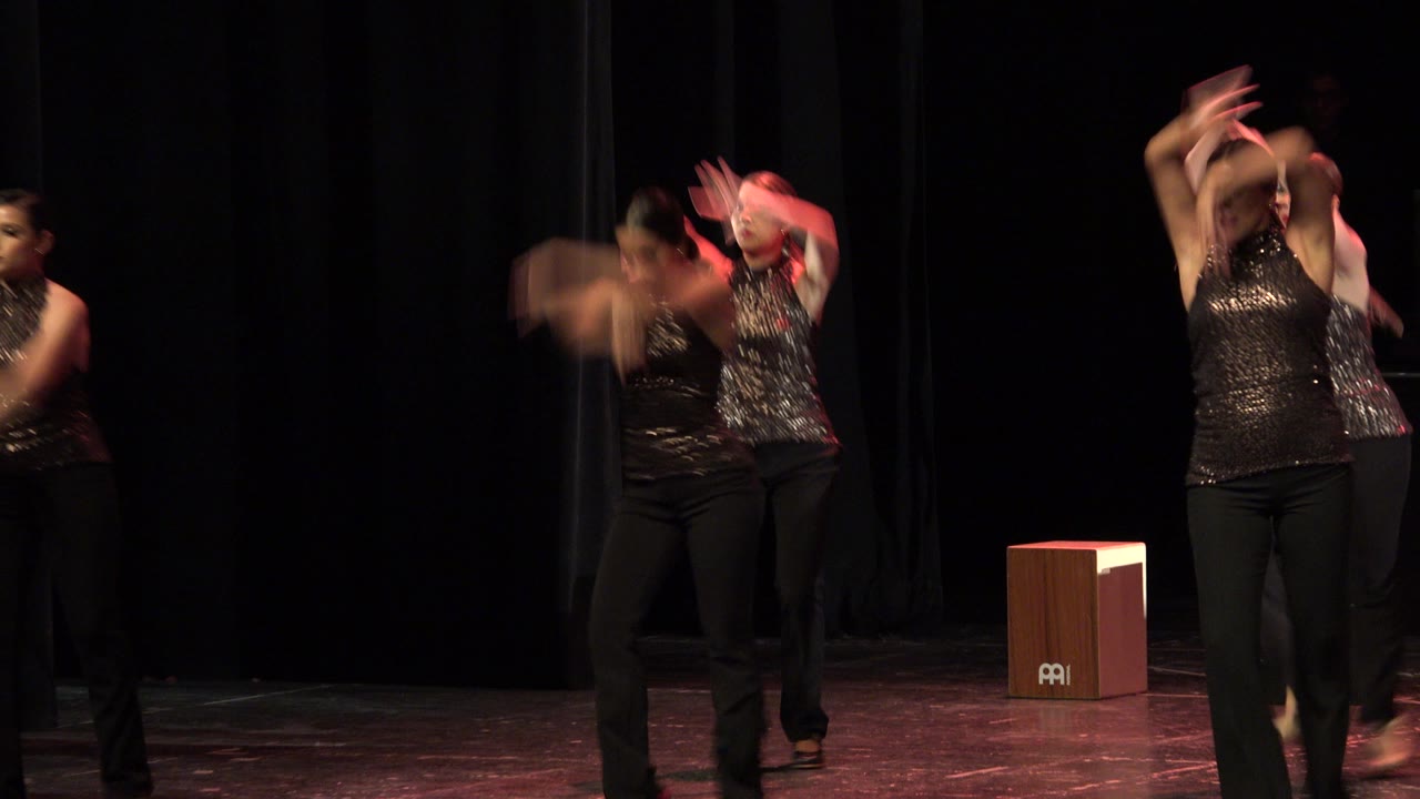 Women dancing on a dark stage in black sequined tops.