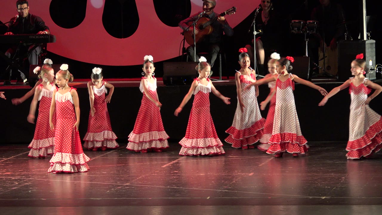 Girls in matching red and white costumes continue the recital dance in Cabo San Lucas, Mexico, with the band positioned on the rear platform.