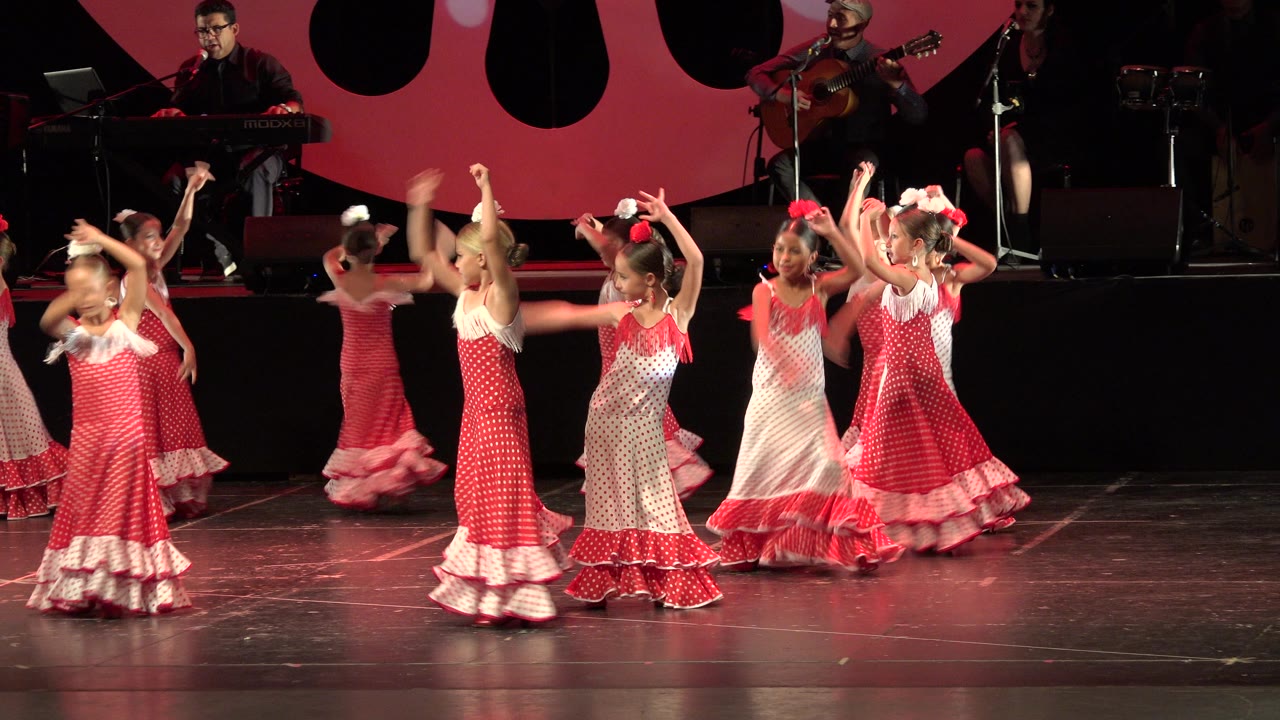 Girls in matching red and white dance costumes cluster near center stage.