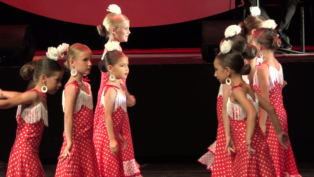 The dancers shift into a line-like arrangement in Cabo San Lucas, with two children facing the camera and others turned sideways or away.