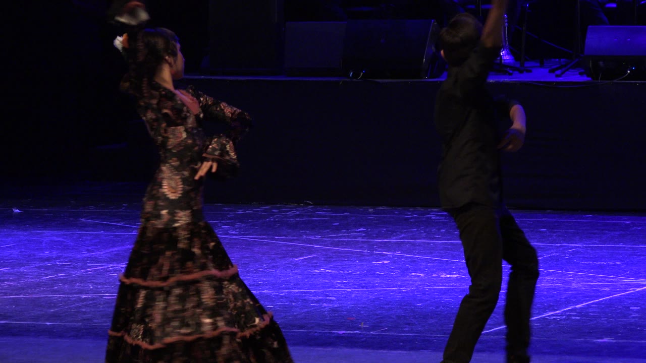 Two young dancers on a blue-lit stage during a choreographed routine.