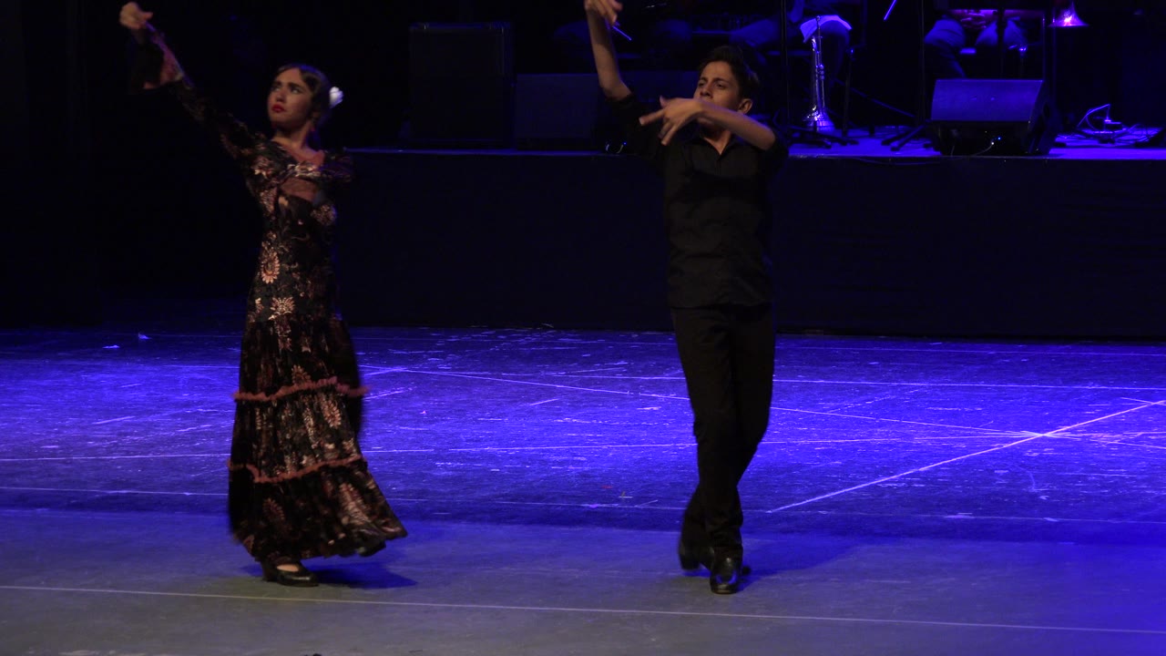 Two children dance on a blue-lit stage.