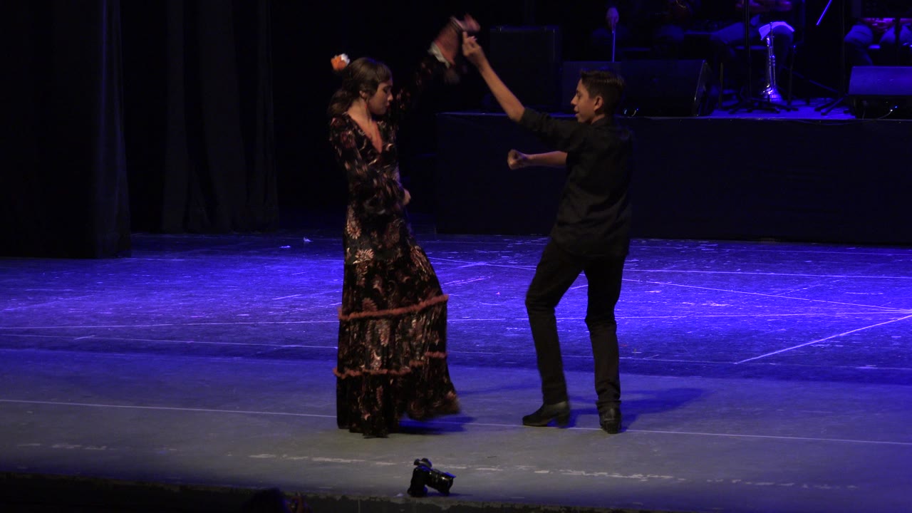 Two teenagers dance on a blue-lit theater stage.
