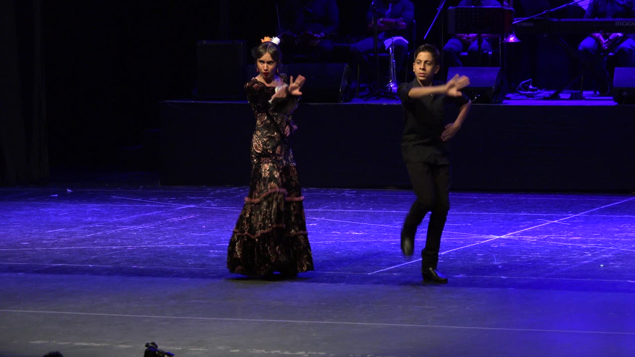 Two dancers perform on a blue-lit stage.
