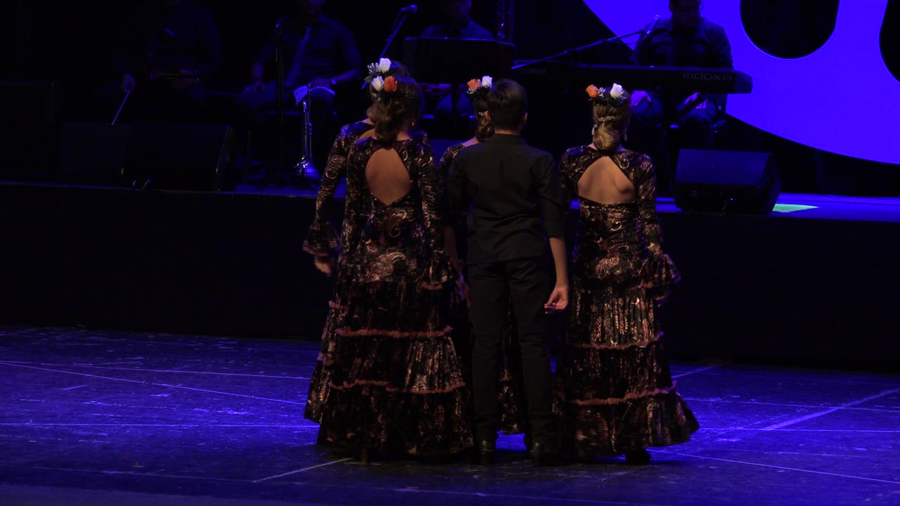 Dance trio stands closer together under purple-blue light.
