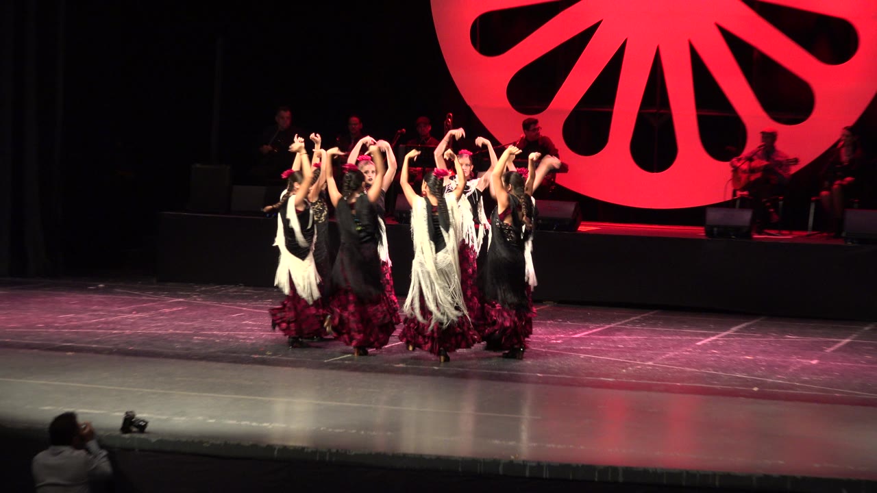 Dancers in costume face inward in a tight circle.