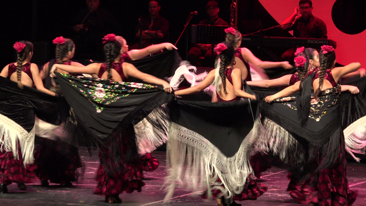 At 0:01 in Cabo San Lucas, Mexico, the dancers keep their shawls lifted as one performer points across the group and musicians remain visible behind them.