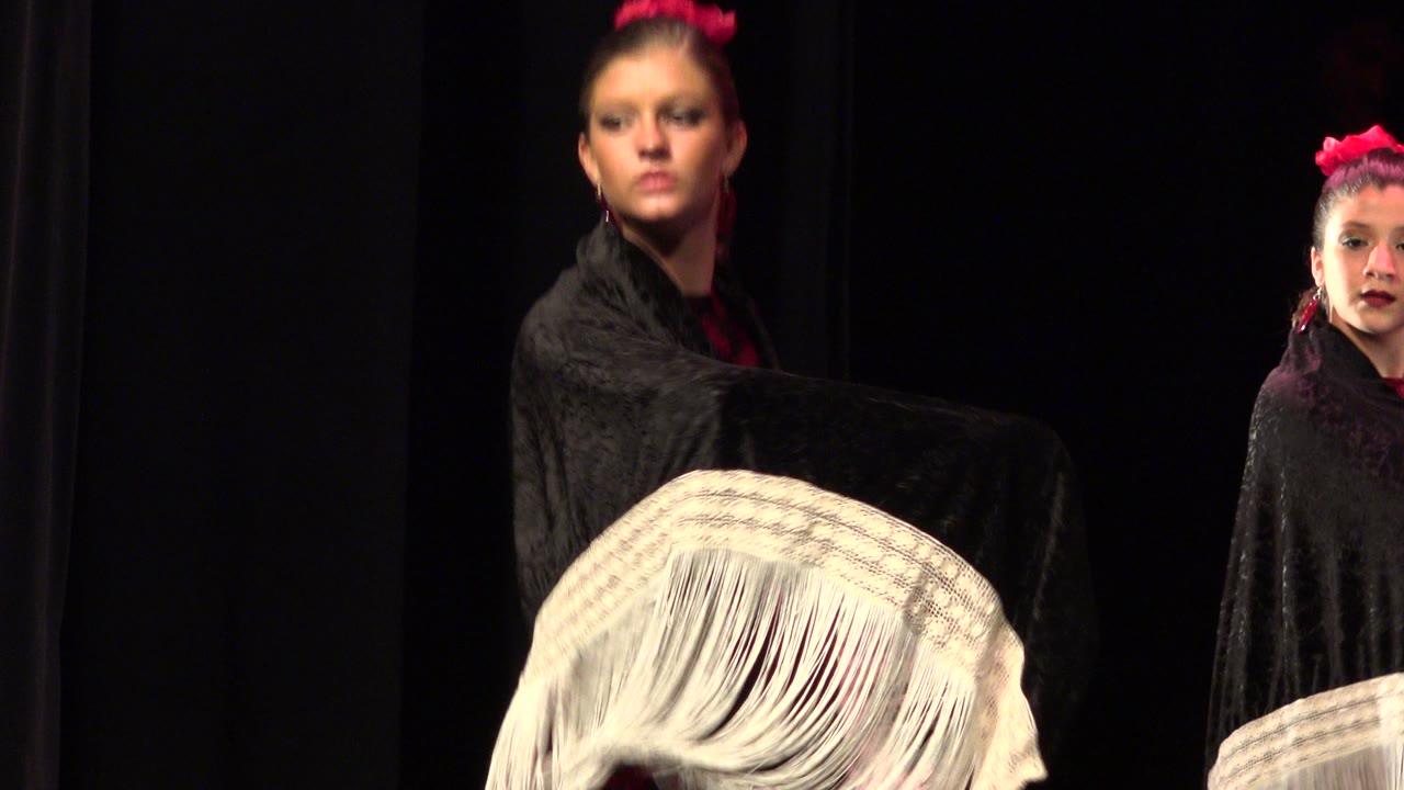 Young dancers on stage with shawls and dark curtains.