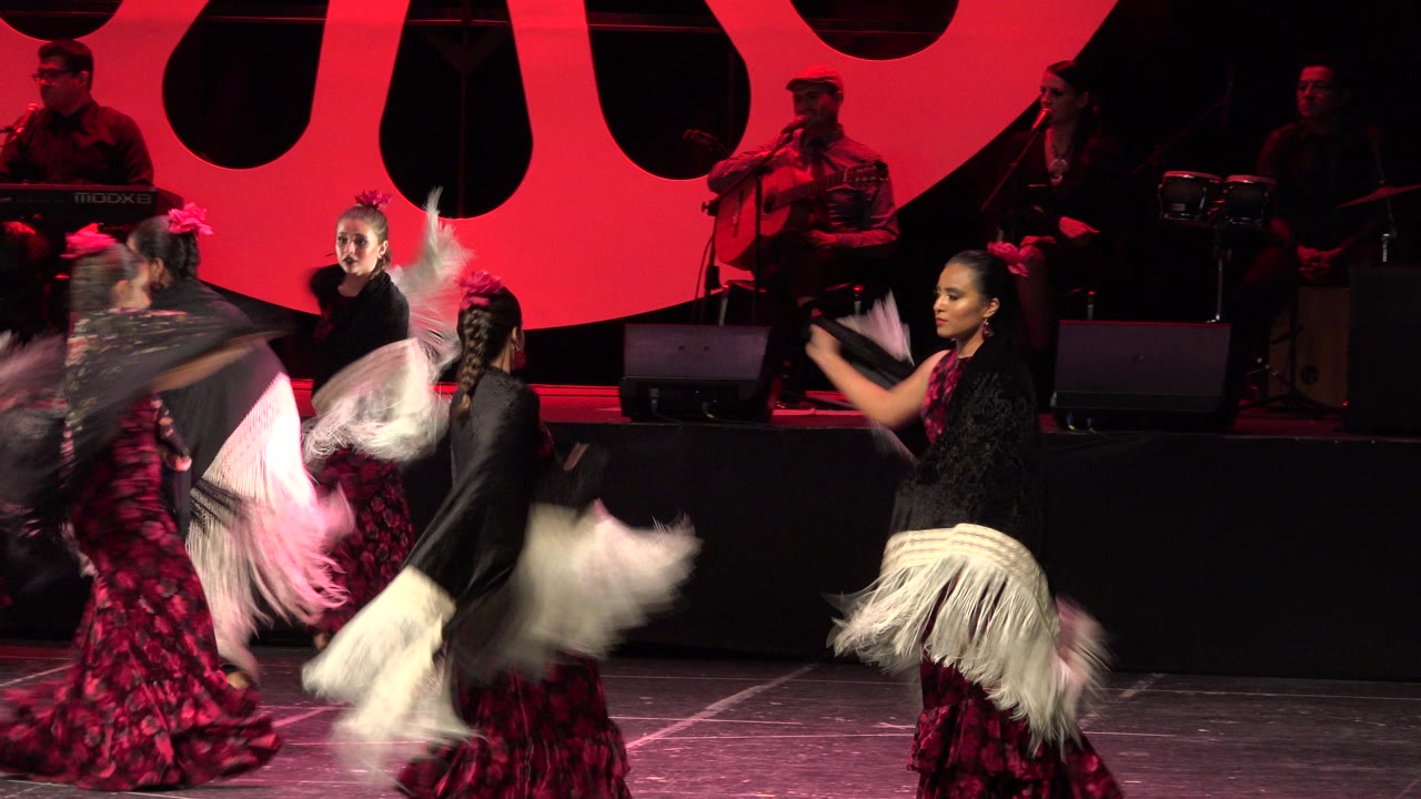Dancers sweep shawls across the stage in front of musicians.