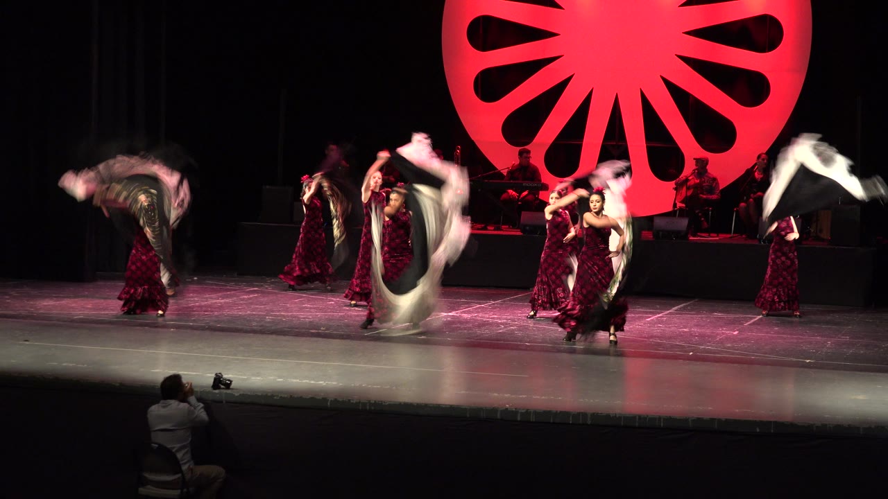 Dancers sweep white and black shawls across a theater stage.