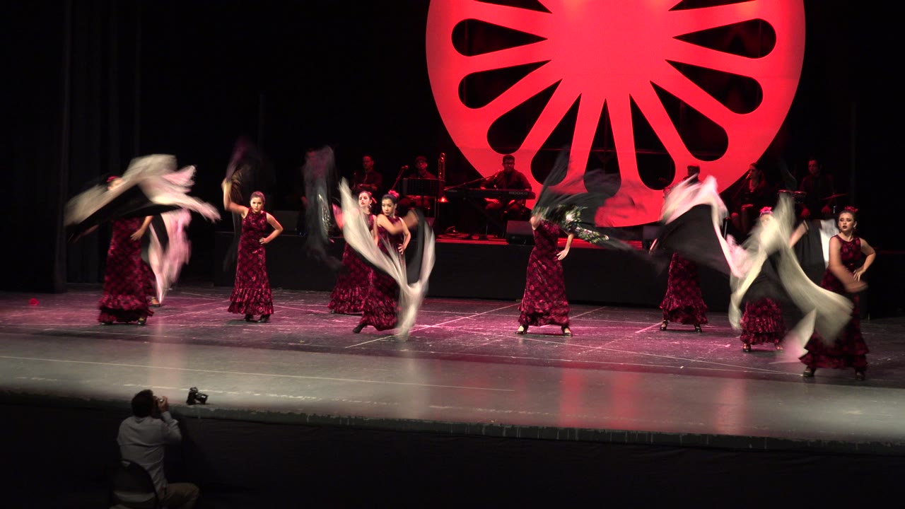 In Cabo San Lucas, the dancers continue their formation while sweeping white and black shawls create motion blur across the red-lit stage.